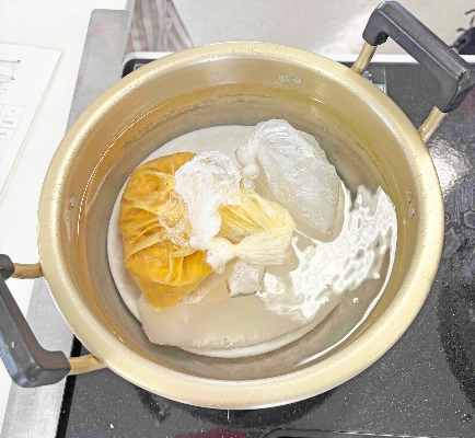 12-鍋の底や壁面にくっつかないよう、お米と卵のポリ袋を入れます