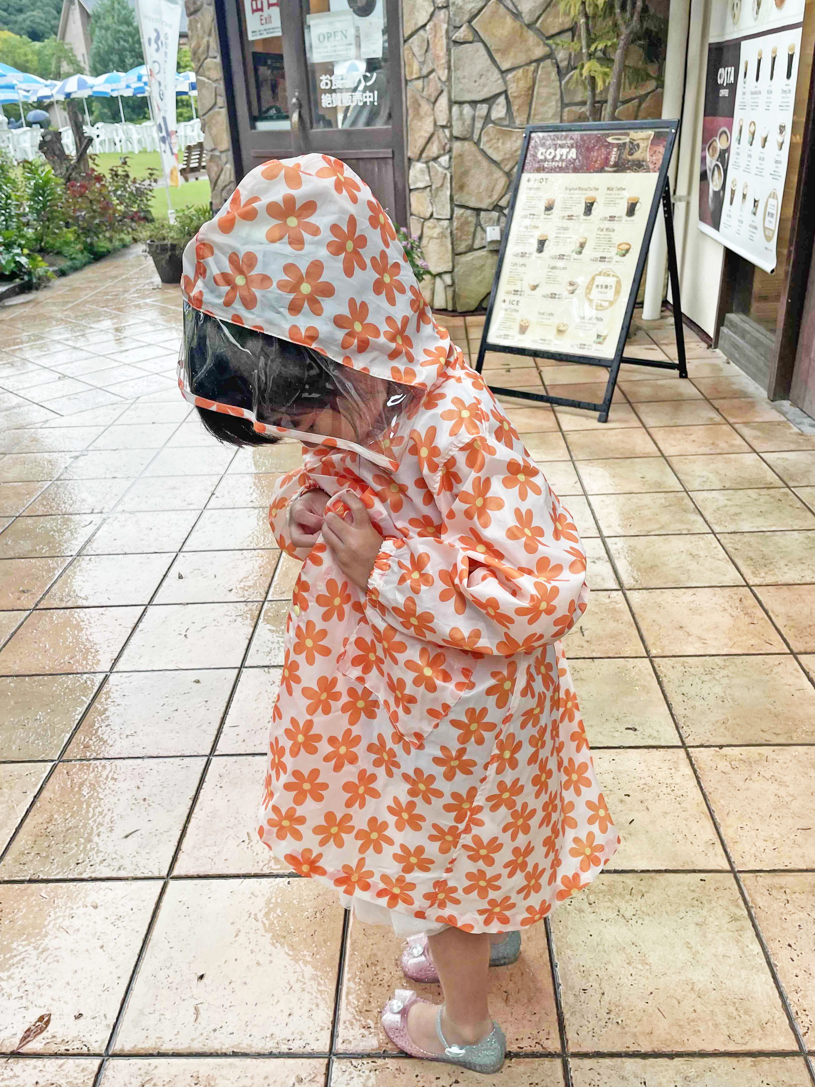 13 パン屋の前でレインコートを着るの娘