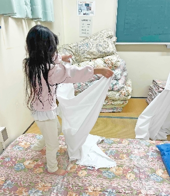 08張り切ってシーツを敷く娘